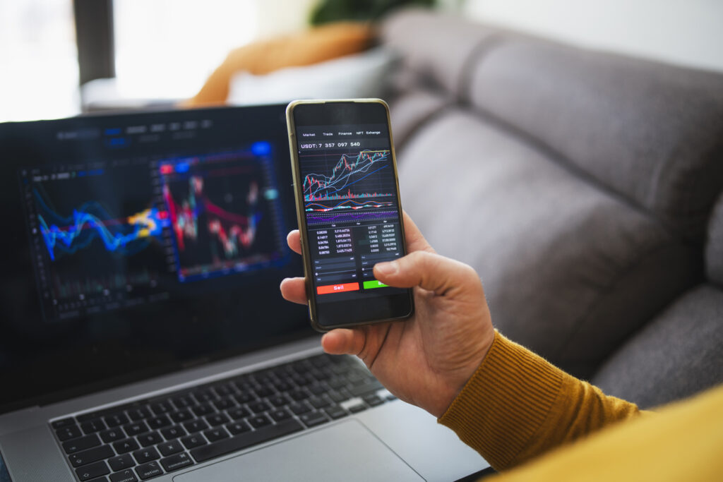 Darstellung von Krypto-Trading auf Mobilgerät und Laptop – Symbolbild für steuerliche Beratung zu Kryptowährungen und Kapitalvermögen in Österreich